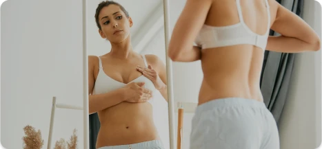 Woman measuring progress in front of mirror after breast augmentation – Ditesheim Cosmetic Surgery